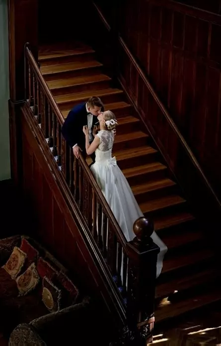 Fotografia ukazująca Młodą Parę na drewnianych schodach Bursztynowego Pałacu
