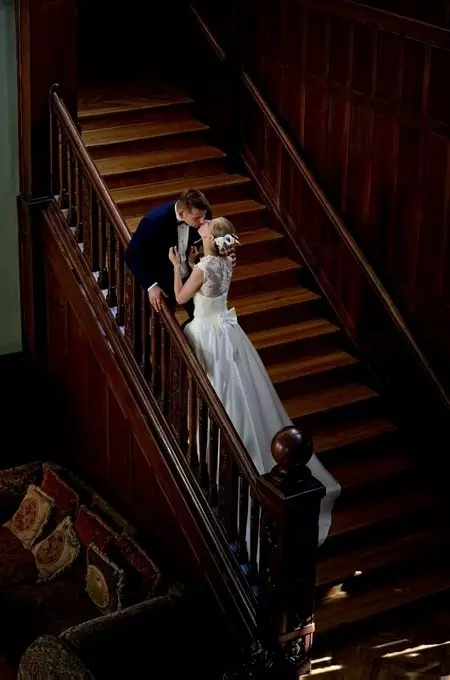 Całująca się para zakochanych na długich i stromych drewnianych schodach starego pałacu