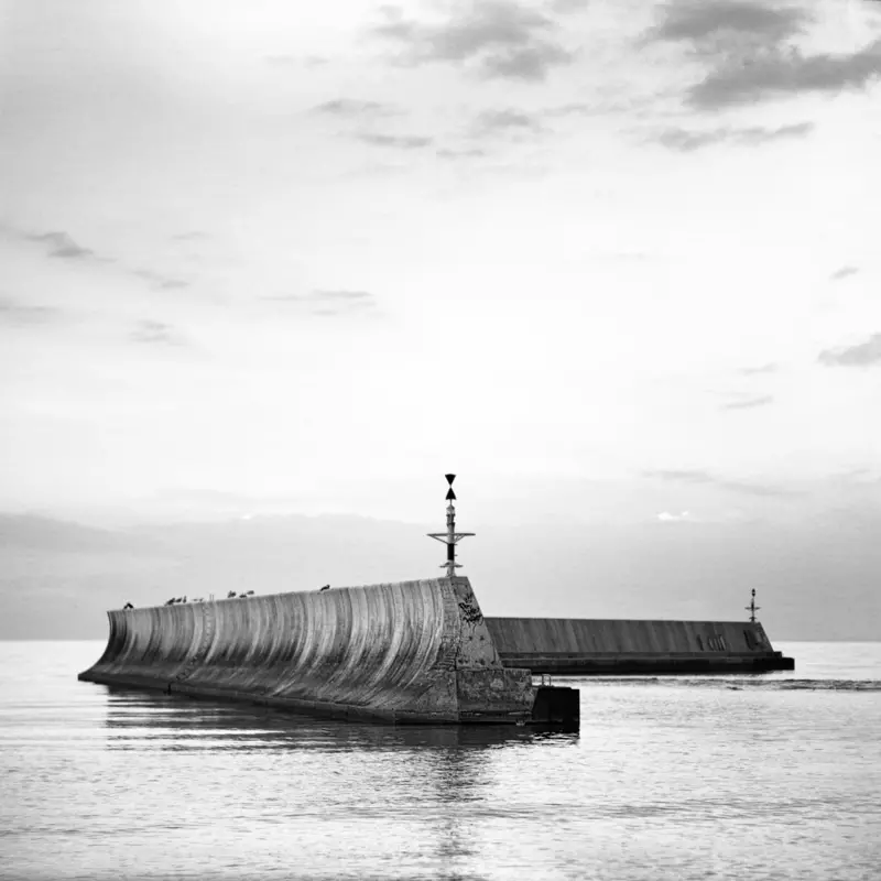 Krajobraz morski z budowlą betonową w kształcie bumerangu osadzoną na morzu bez dostępu z brzegu