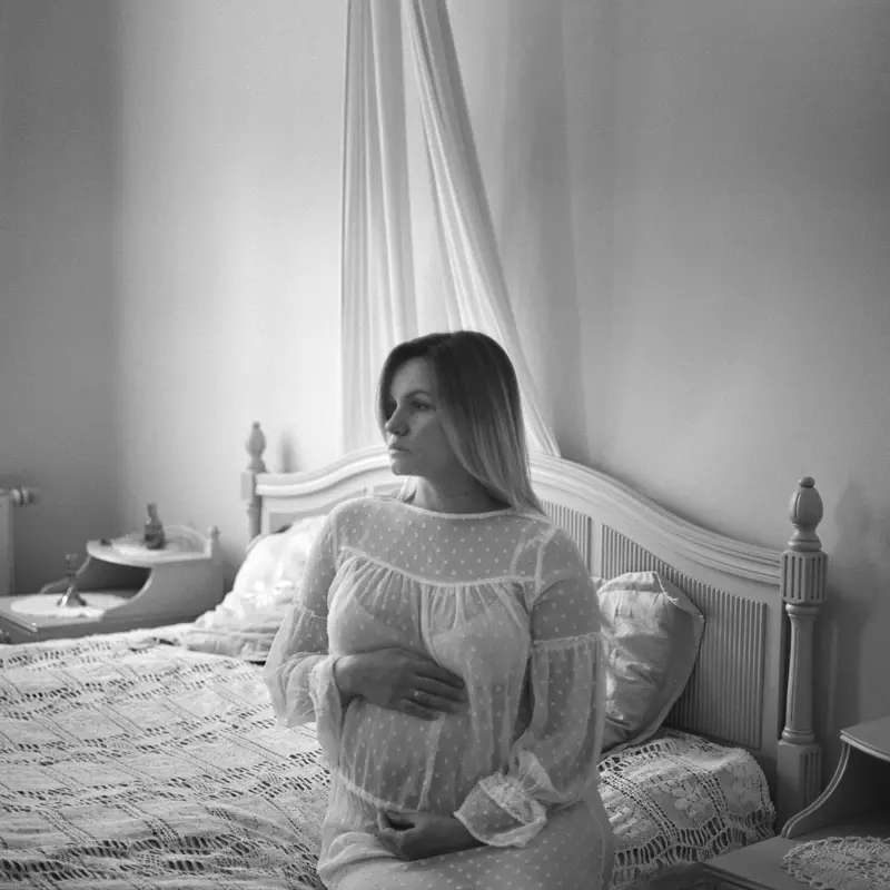 portret ciążowy kobiety siedzącej na zabytkowym łóżku Pałacu