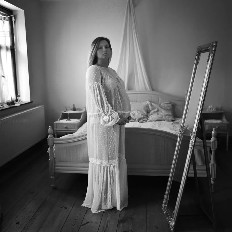 Stojąca przed zabytkowym lustrem kobieta w ciąży