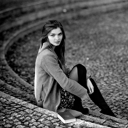 Siedząca dziewczyna na kamiennych schodkach z książką obok siebie