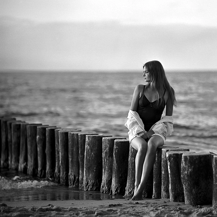 Kobieta siedząca na falochronach na plaży w Ustroniu Morskim