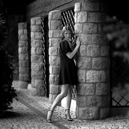 Dziewczyna w butach na wysokim obcasie oparta o kamienne filary