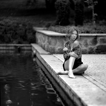 Dziewczyna siedząca na betonowej posadzce w sukience nad brzegiem jeziorka