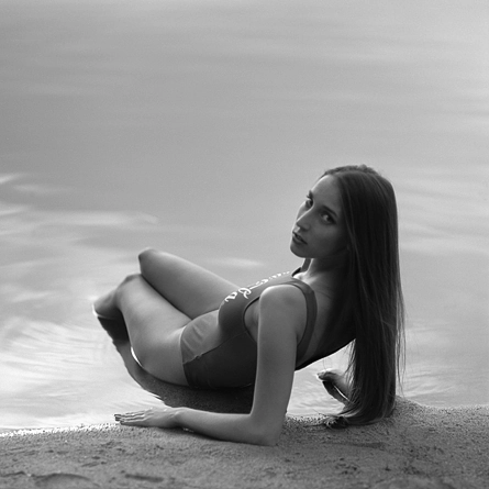 leżąca na brzegu dziewczyna w kąpielowym body