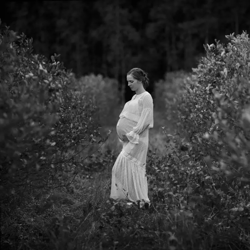 Zdjęcie pokazujące całą postać kobiety w ciąży ubranej w kremową sukienkę ciążową