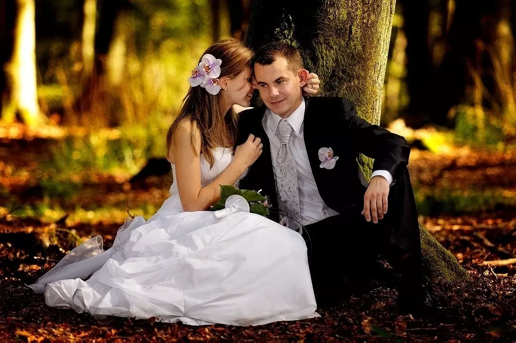 Przytulona do siebie ślubna para w bukowym lesie