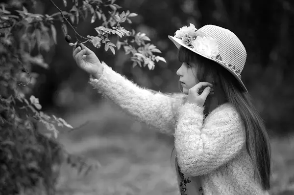 Piękny plenerowy widok dziewczyny w kapeluszu dotykającej owoców krzewu