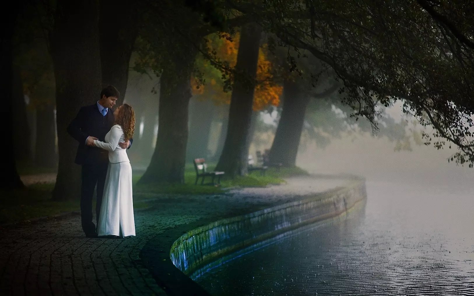 Malownicza scena ukazująca scenę przytulania się zakochanej pary nad jeziorem o poranku