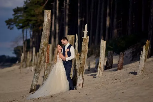 Żona i mąż stojący na plaży przy kikutach starych drzew